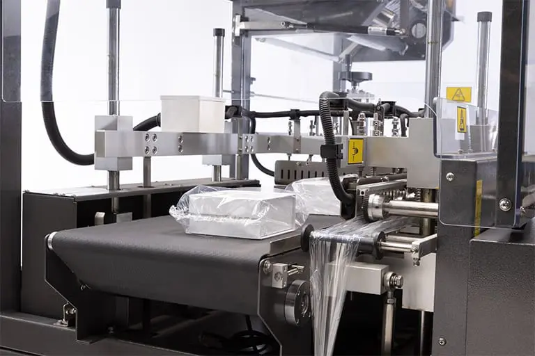 Packaging machine wrapping plastic around products. Packaging machine wrapping plastic around products.