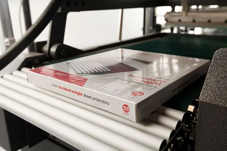 Pack of sheet protectors on conveyor belt.