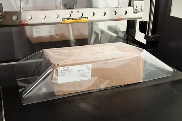 Cardboard box wrapped in clear plastic film.