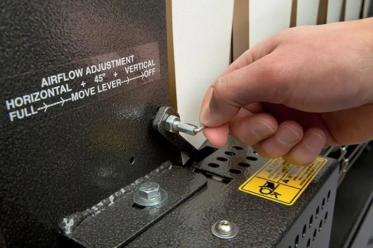 Hand adjusting airflow lever on equipment.