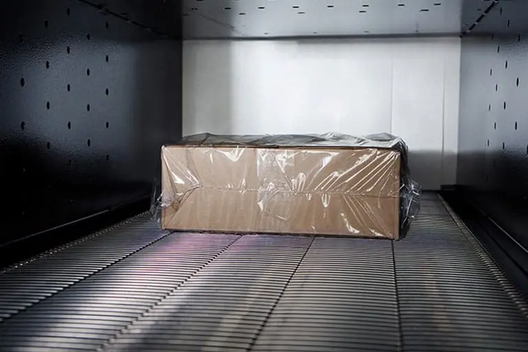 Box wrapped in plastic on conveyor belt.
