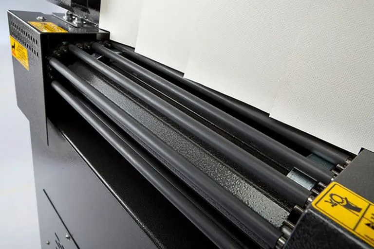 Printing machine with paper and rollers.