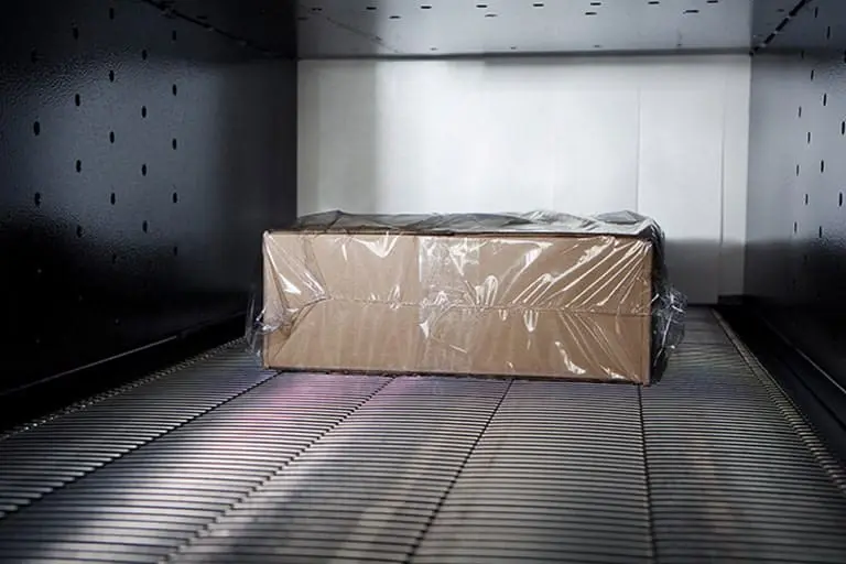 Box wrapped in plastic on conveyor belt.