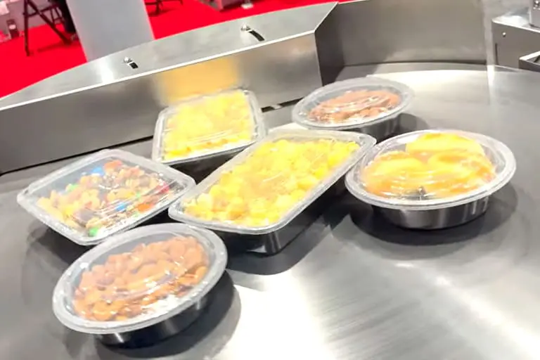 Packaged food containers on a conveyor belt.
