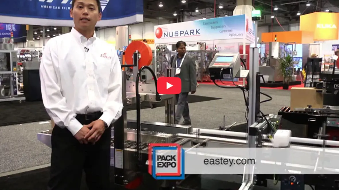 Man presenting packaging equipment at trade show.