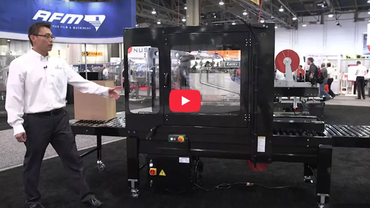 Man presenting industrial packaging machine at expo.