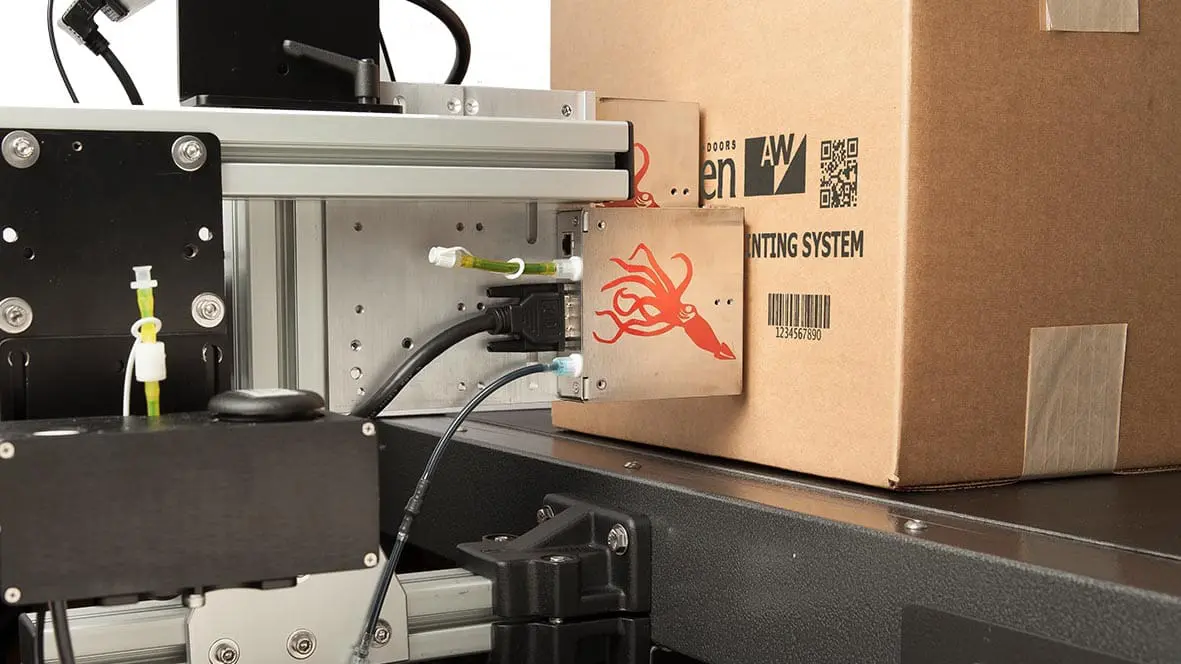 Industrial printing system labeling a cardboard box.