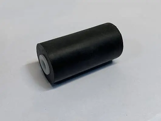Black cylindrical roller on a gray surface.
