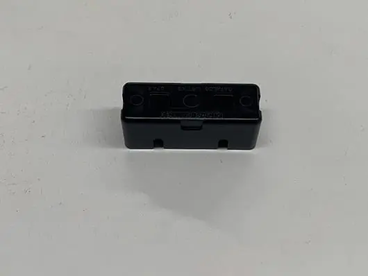 Black rectangular electronic component on white surface.