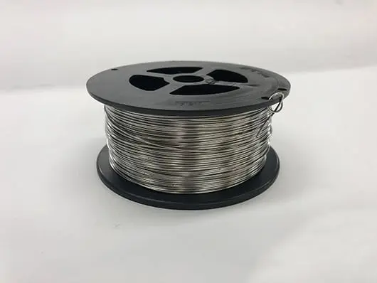 Spool of metallic wire on table.