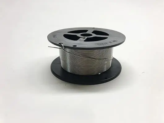 Spool of metal wire on white background.