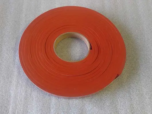 Red roll of tape on gray surface.