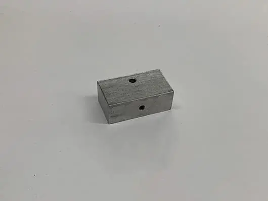 Rectangular metal block with two holes.