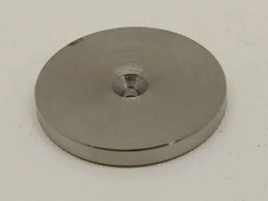 Metal disc with central hole on surface.