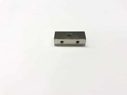 Metal block with three holes, white background.