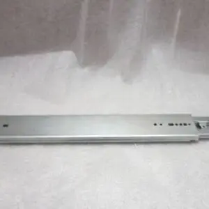 Metal drawer slide on a gray surface.