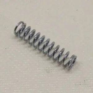 Metallic coil spring on textured surface.