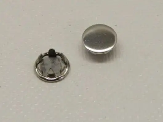 Two metal snap fasteners on surface.