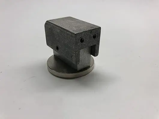 Metallic part on a round base.