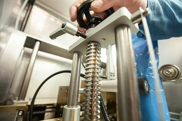 Person adjusting industrial machine gears.