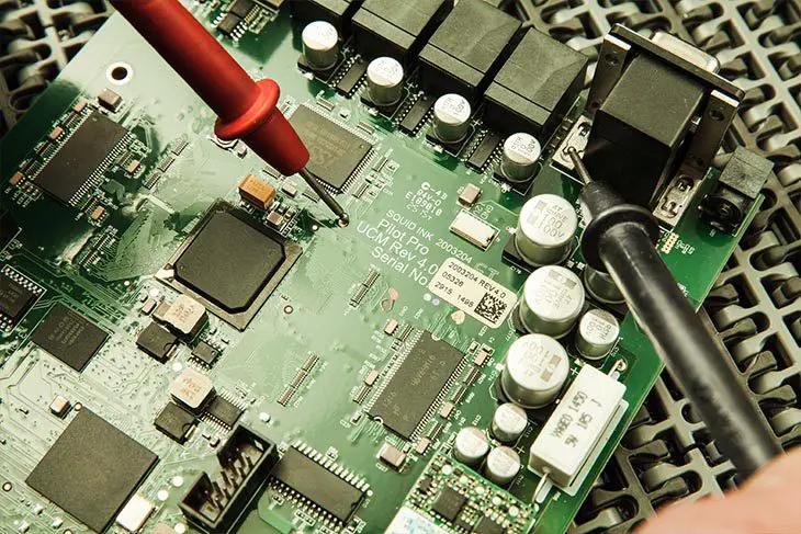 Circuit board being tested with multimeter.