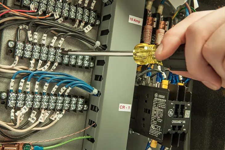 Electrician using screwdriver on wiring.